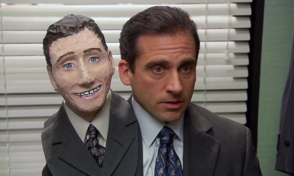 Steve Carell as Michael Scott wearing a second head made of paper mache in one of the best Halloween TV episodes from The Office.