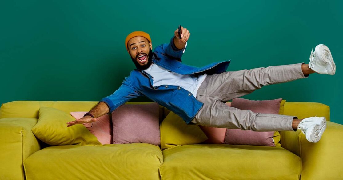 Man jumping onto a couch to watch TV