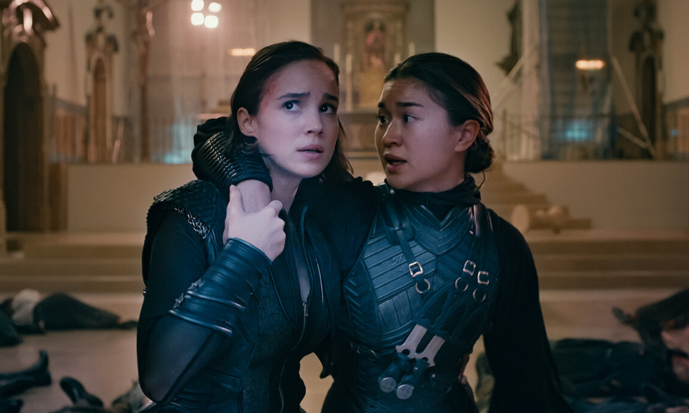 WarriorNun1000x600 One warrior nun wraps an arm around another; they both look worried.