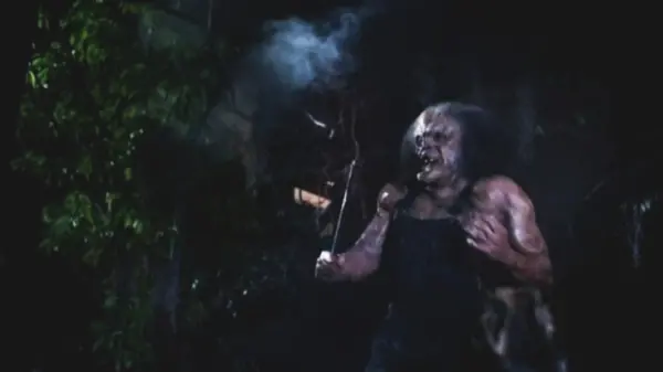 A wild-eyed disfigured redneck, hatchet raised, ready to chase a victim. A scene from Hatchet, one of several free streaming horror movies to watch right now.