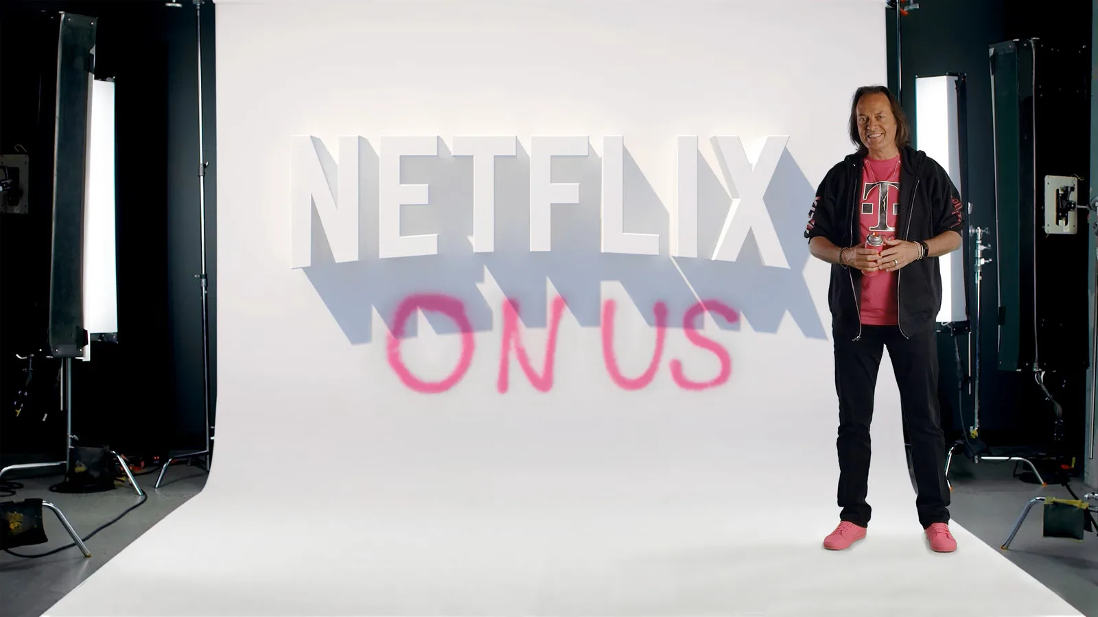John Legere Netflix On Us A man standing in front of the Netflix logo with “ON US” written below in spray paint.