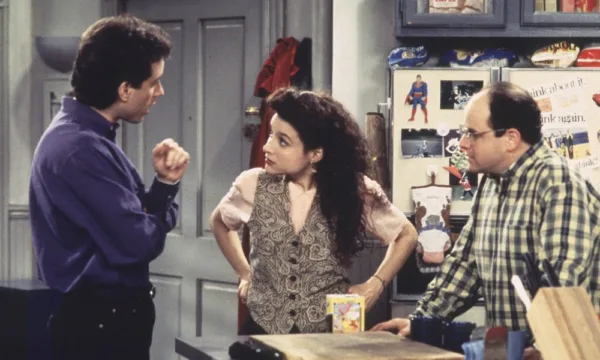 Seinfeld1000x600 Jerry, Elaine, and George from Seinfeld stand around talking in the kitchen.