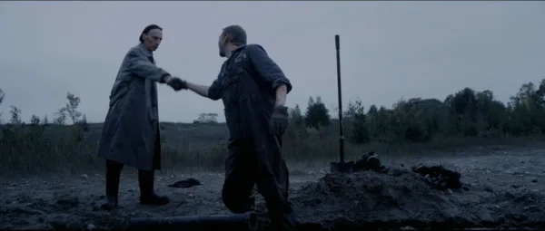 An image of two men shaking hands near a septic tank. A scene from Septic Man, one of the 13 Nastiest Movies on Tubi.