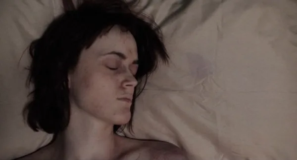 Image of a woman sleeping. She has bruises or lesions on her face. A scene from Thanatomorphose, one of the 13 Nastiest Movies on Tubi.