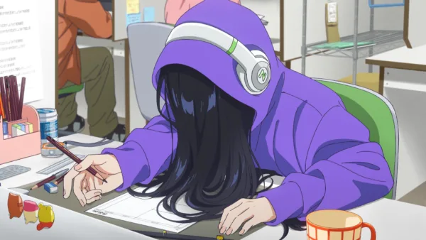 A woman with long black hair covering her face is drawing at a desk.